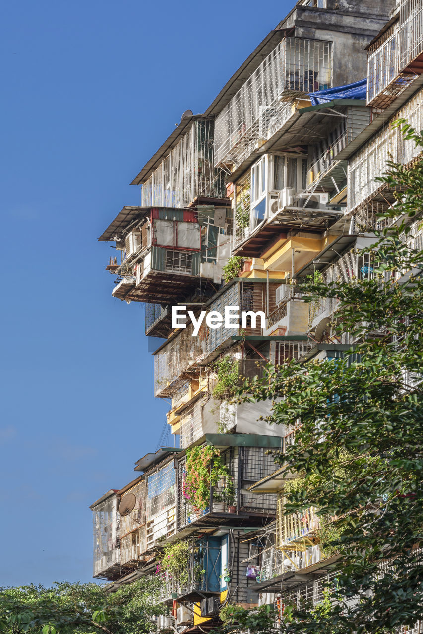 Low angle view of buildings in town against clear blue sky