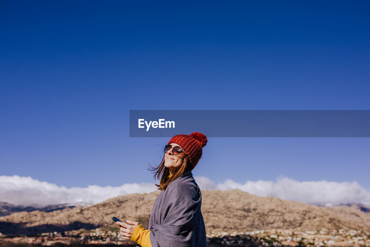 Side view of woman against blue sky