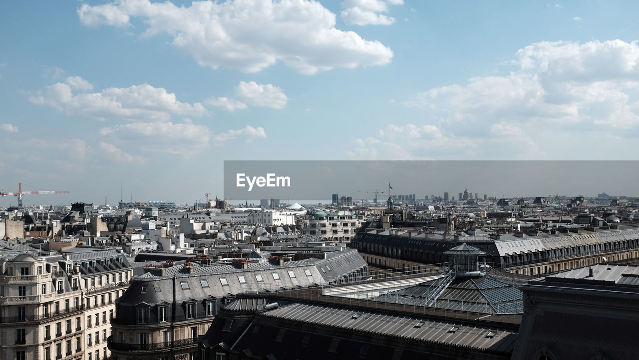 High angle view of city buildings against cloudy sky