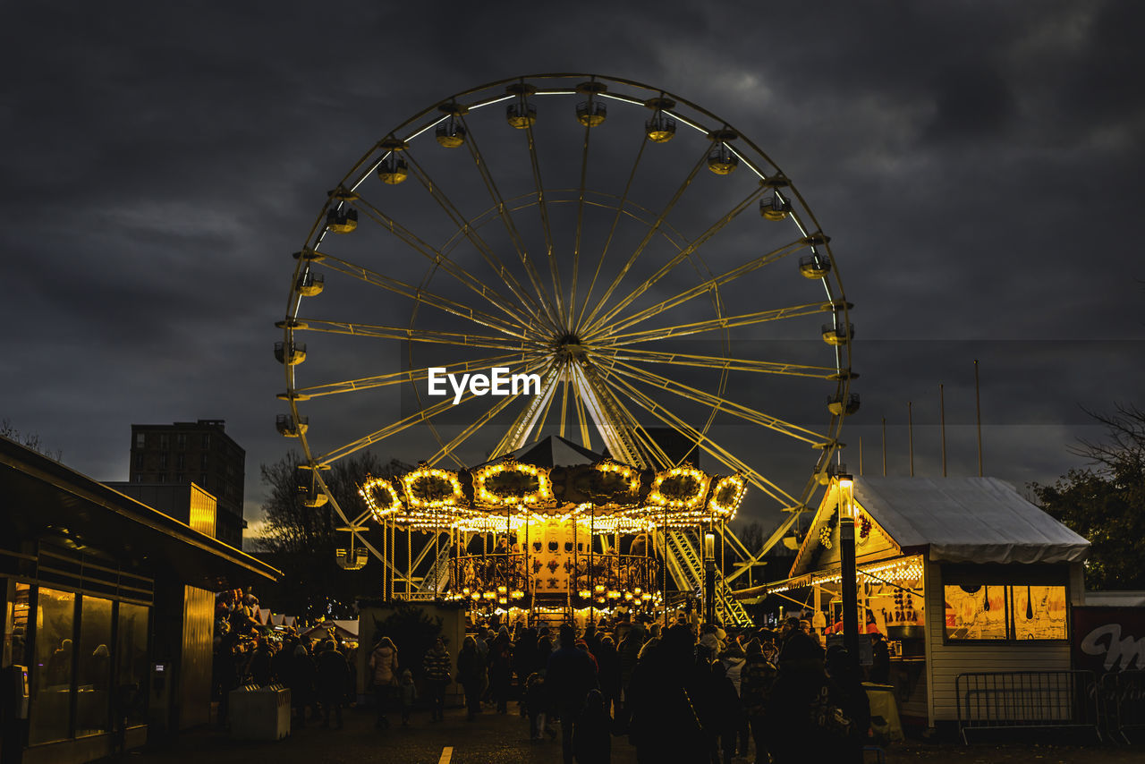 amusement park, amusement park ride, ferris wheel, arts culture and entertainment, architecture, sky, night, illuminated, built structure, recreation, cloud, building exterior, dusk, travel destinations, nature, traveling carnival, city, outdoors, carnival, leisure activity, shape, circle, travel