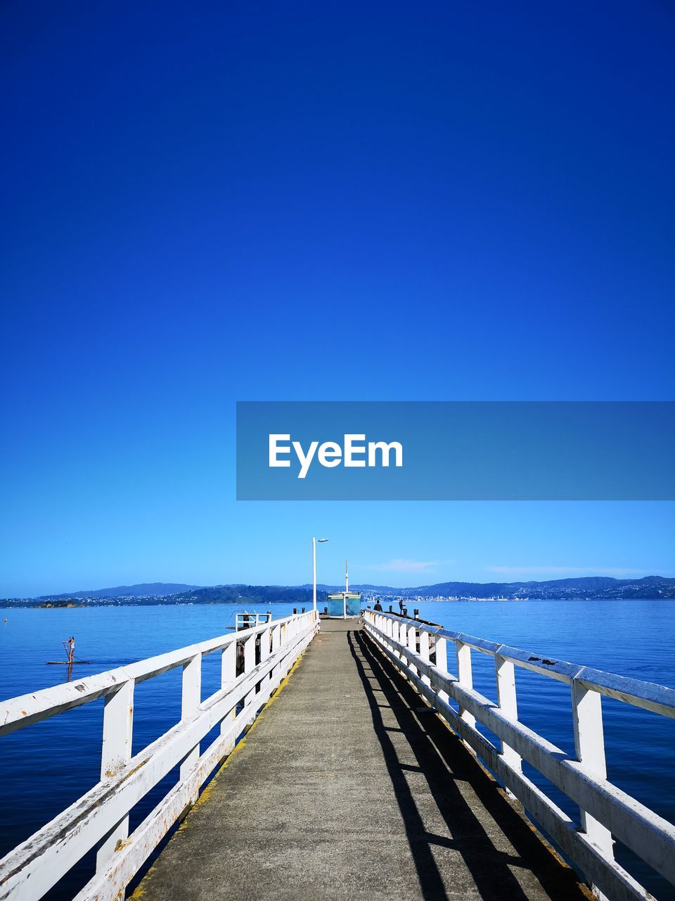 Pier over sea against clear blue sky