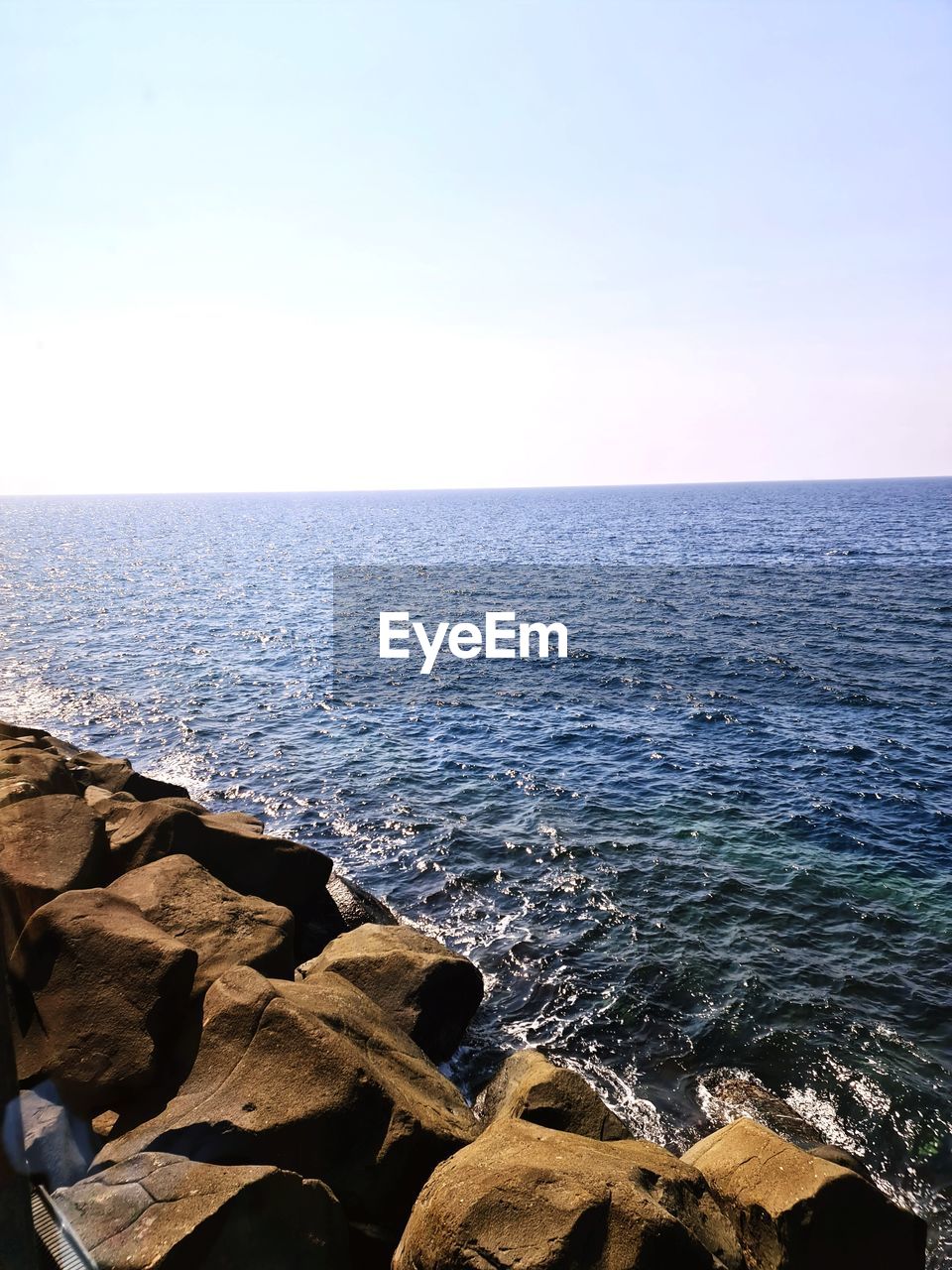 SCENIC VIEW OF SEA BY ROCKS AGAINST CLEAR SKY