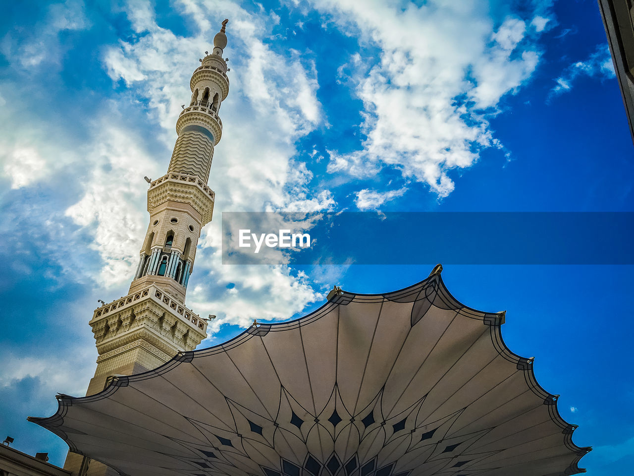 Low angle view of minaret against cloudy sky