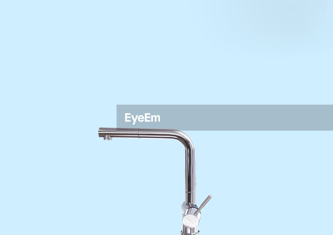 Close-up of faucet over blue background