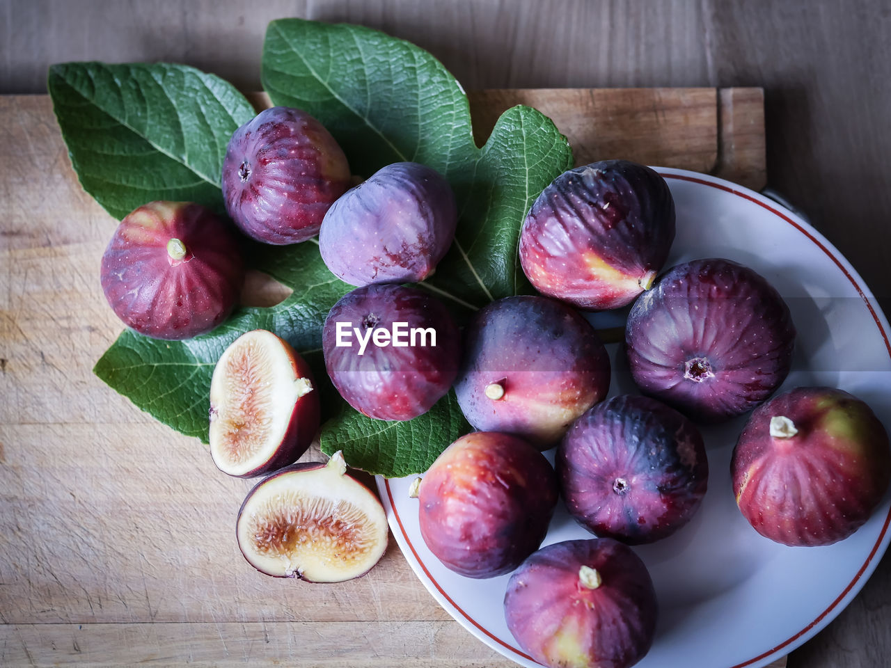 food and drink, food, healthy eating, freshness, wellbeing, plant, fruit, common fig, produce, wood, indoors, no people, high angle view, still life, table, fig, bowl, vegetable, directly above, studio shot, purple, organic, leaf, plate, plant part, slice