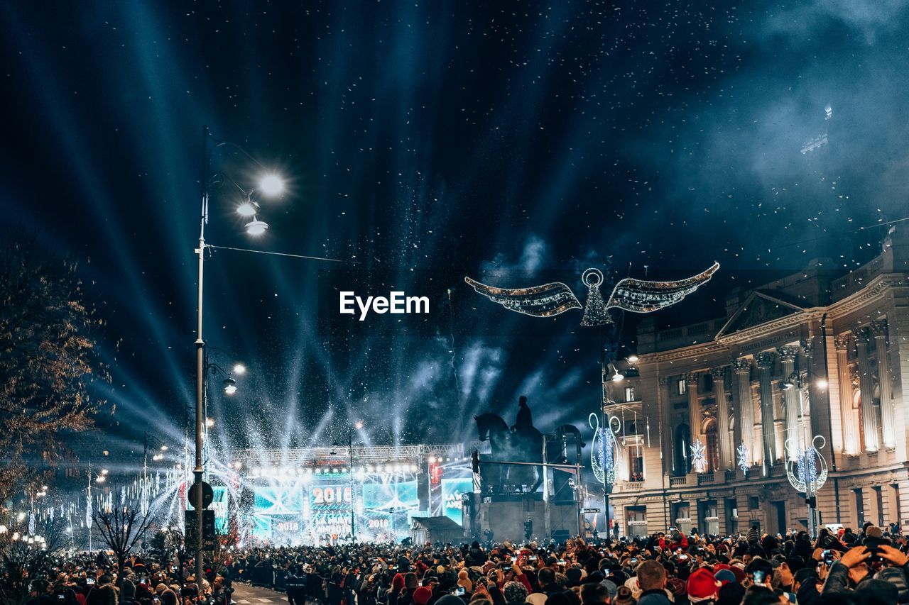 Crowd at music concert against sky at night