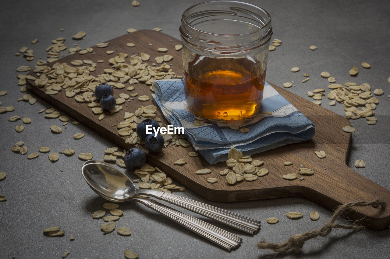 High angle view of maple syrup in jar on cutting board with blueberries and oats at table