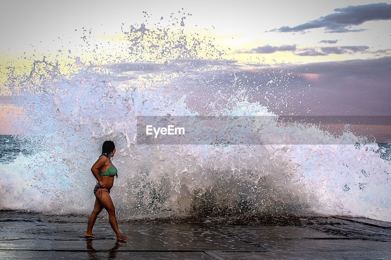 Full length of woman standing in water against sky