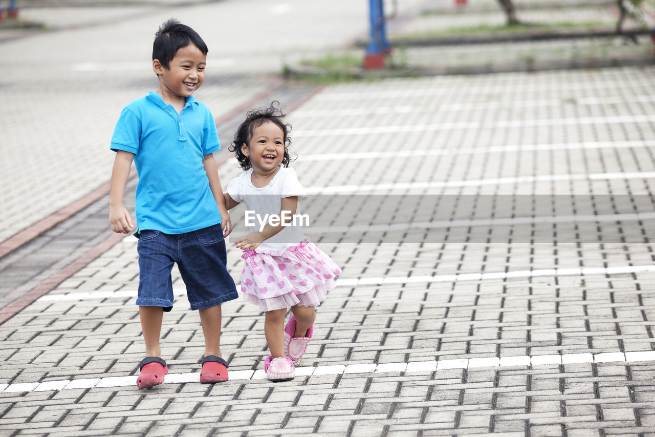 Full length of boy and girl walking on footpath