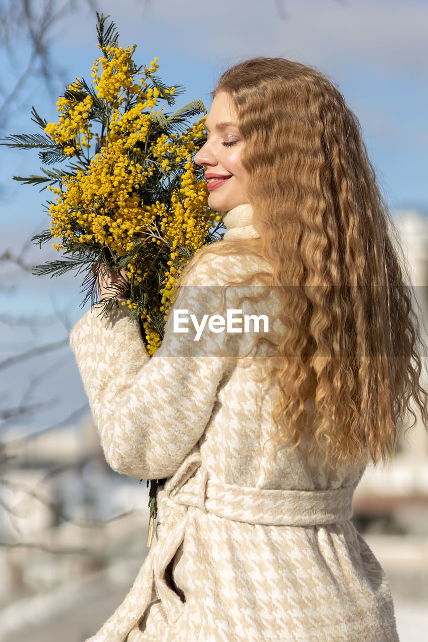 A woman with a bouquet of acacia flowers. the concept of the spring - march 8, easter, women's day.