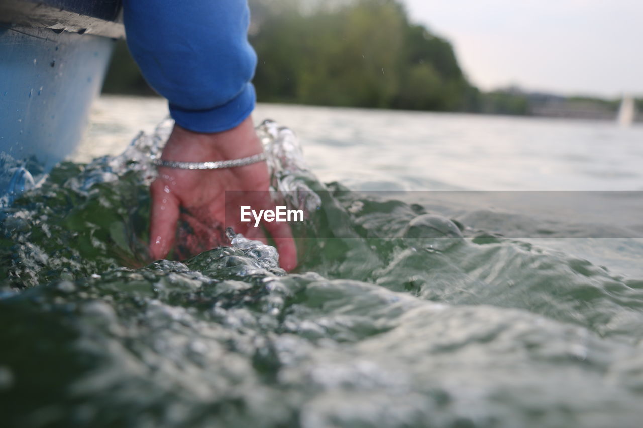 LOW SECTION OF WOMAN STANDING IN SEA WATER