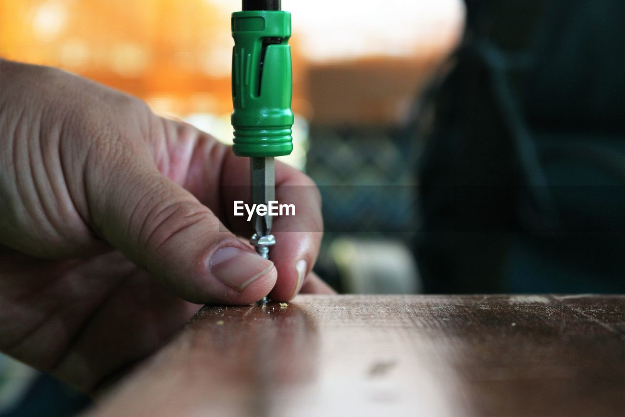 Close-up of hand holding object over white background