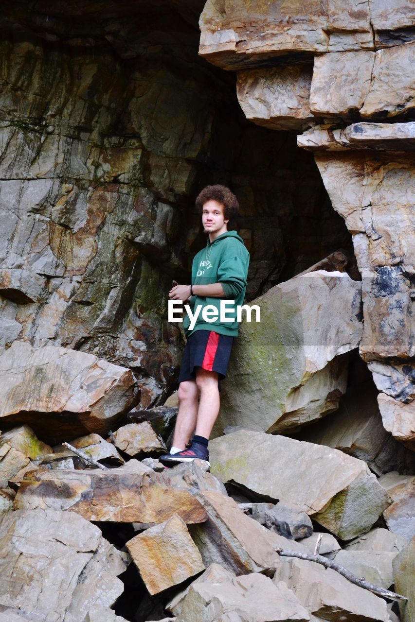 Portrait of smiling teenage boy standing on rock