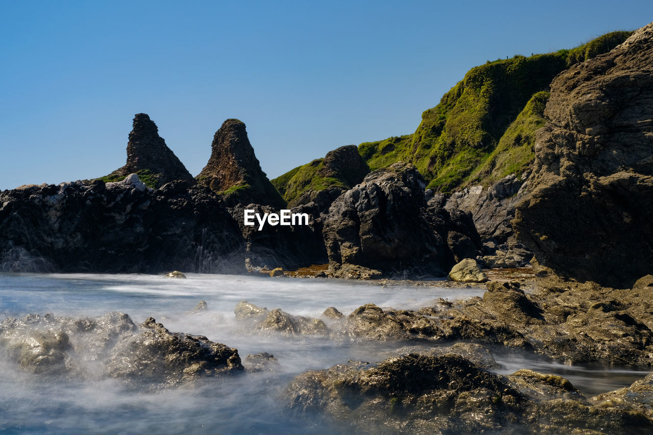 Scenic view of rocks in sea against clear sky