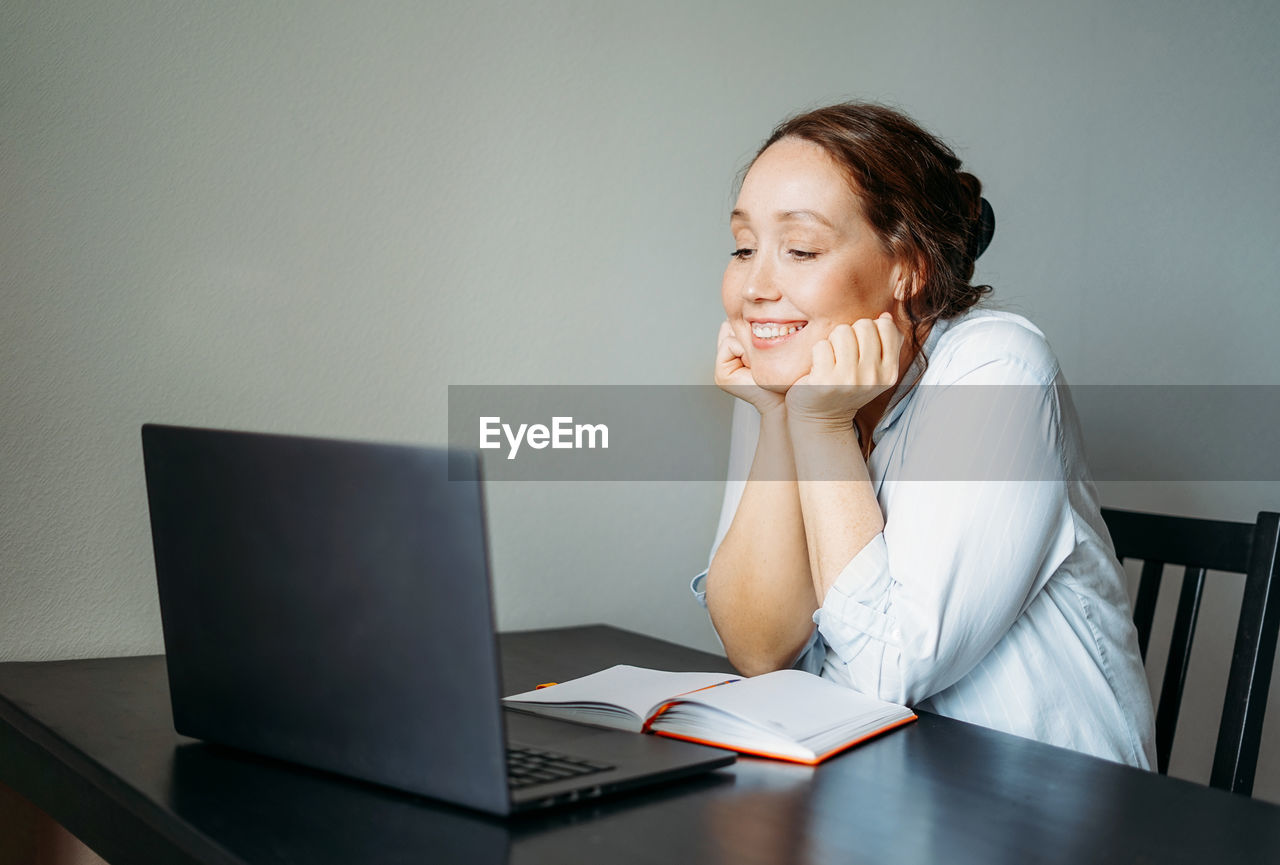 Young woman using mobile phone while sitting on table