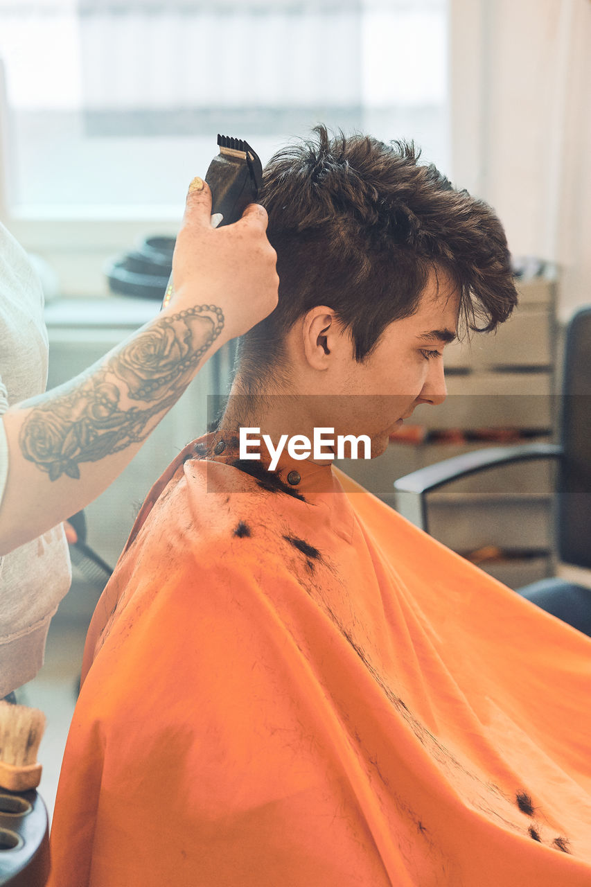 Midsection of woman cutting man hair in salon