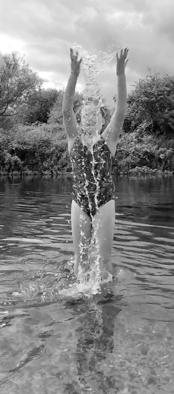 Girl splashing water while jumping in river