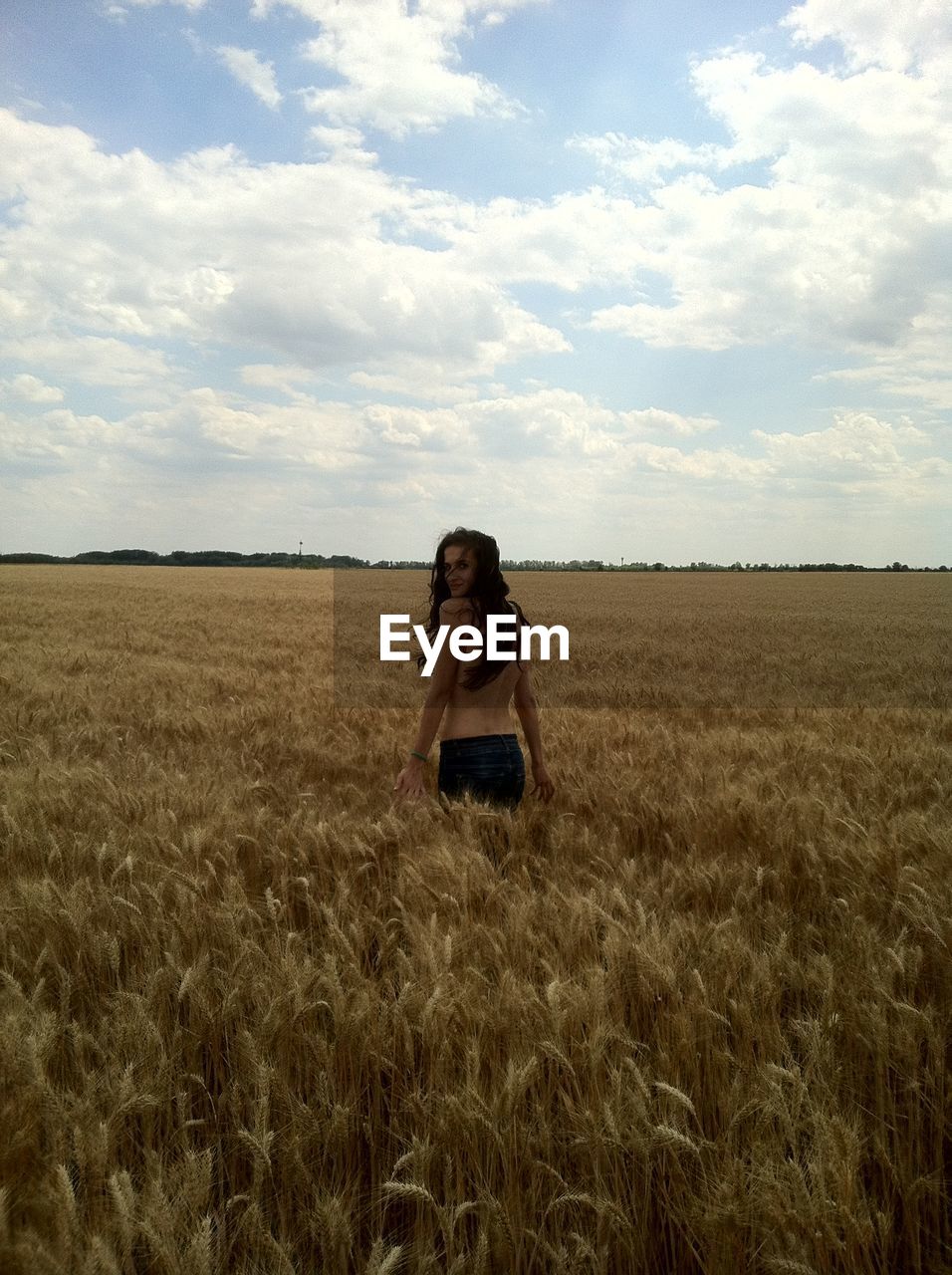 Portrait of topless woman standing amidst wheat field