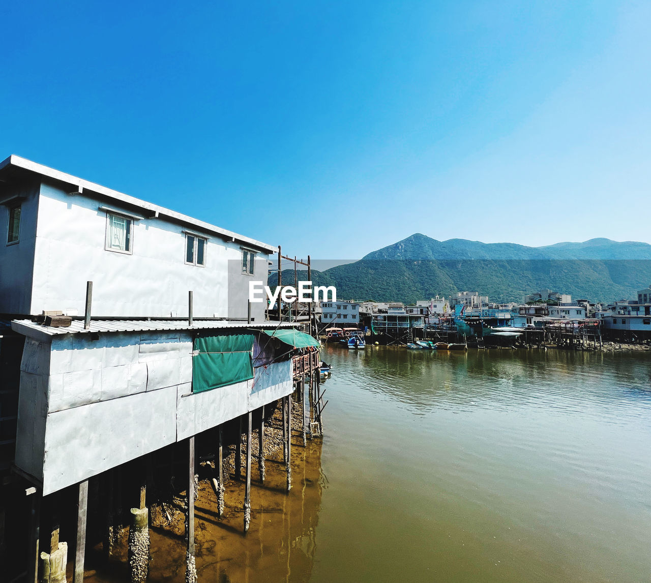 water, architecture, sky, built structure, nature, reflection, sea, stilt house, building exterior, mountain, building, clear sky, no people, house, dock, blue, day, vehicle, transportation, travel destinations, outdoors, nautical vessel, travel, pier, land, tranquility, scenics - nature, residential district, beauty in nature, hut, landscape, vacation, sunny, body of water, beach