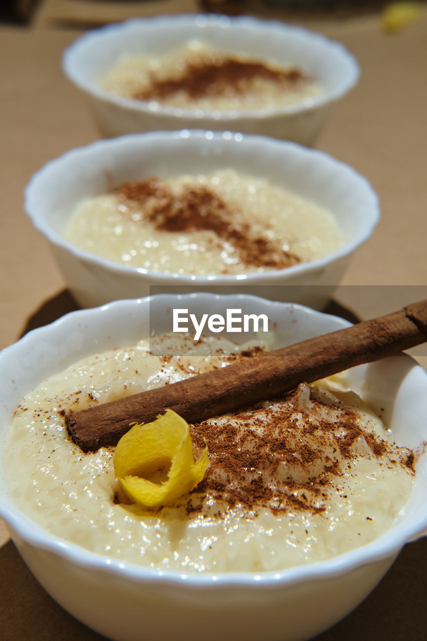 Three rice pudding desserts on a brown base decorated with cinnamon a