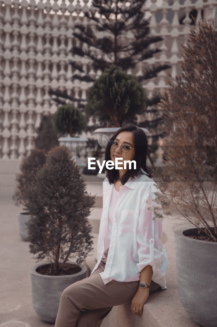 Portrait of young woman standing against wall