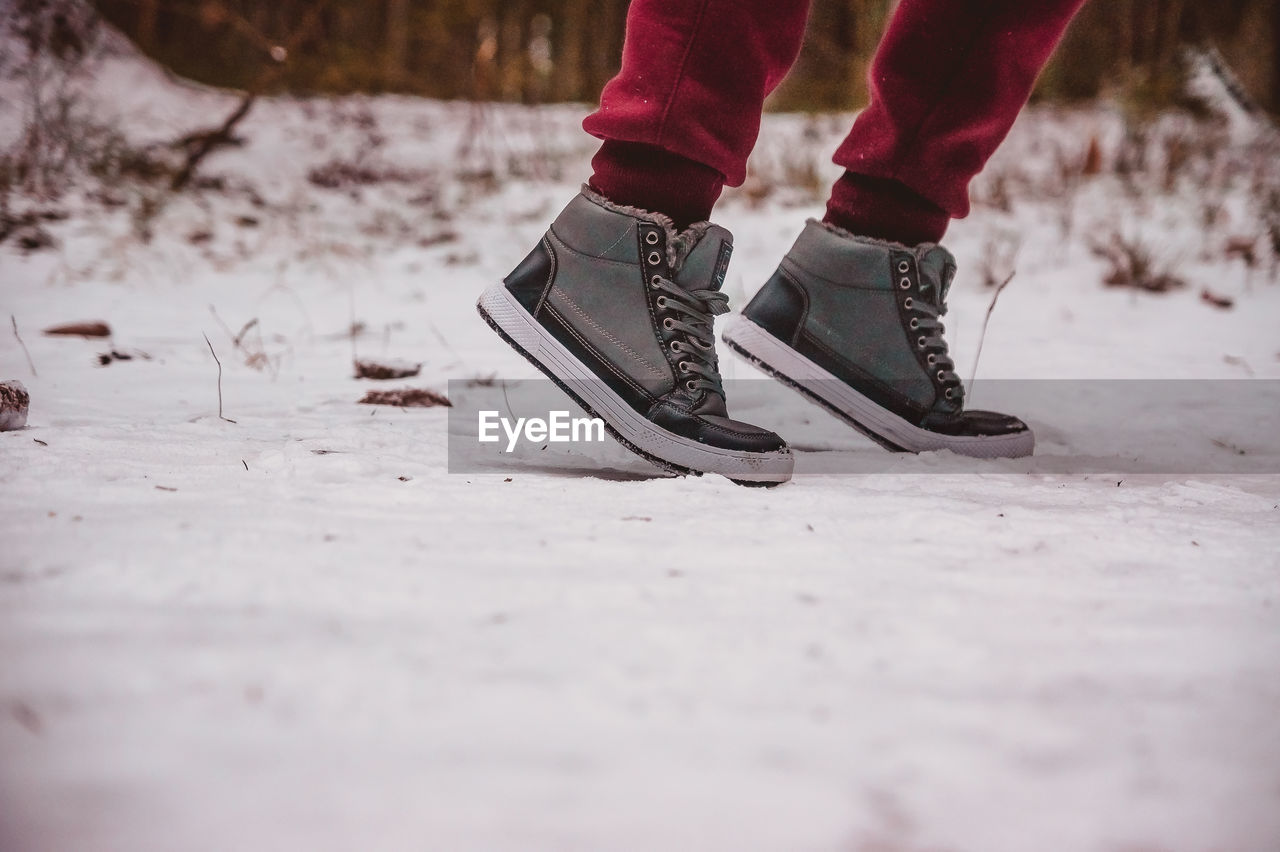 The legs of a person about to run along a snowy winter path