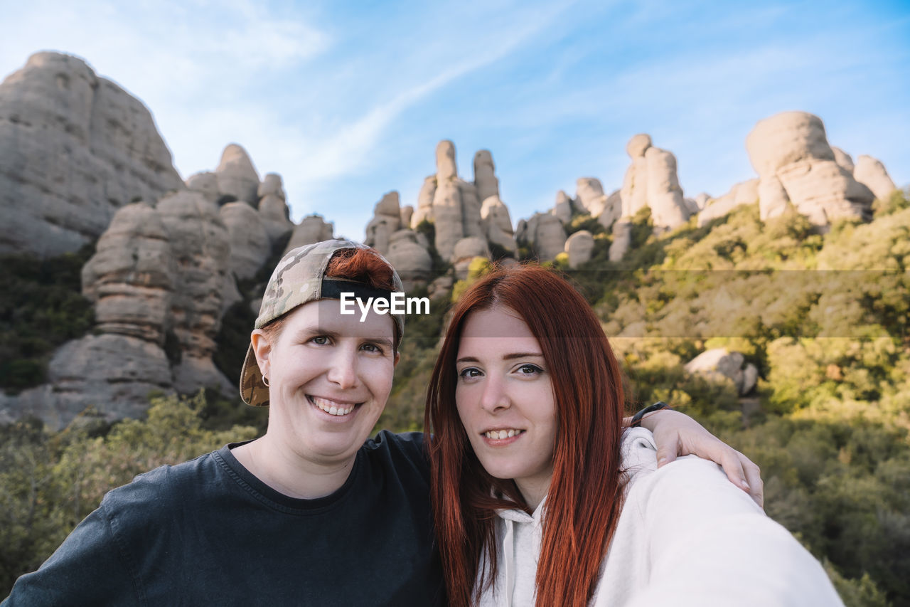 Portrait of young woman standing against mountain