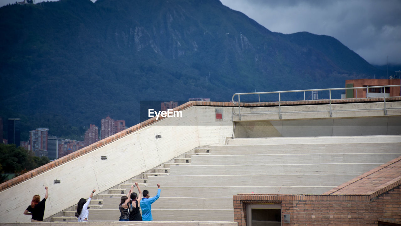 People standing by staircase against mountains