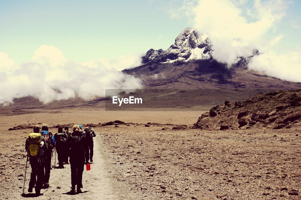 Rear view of people on desert against sky