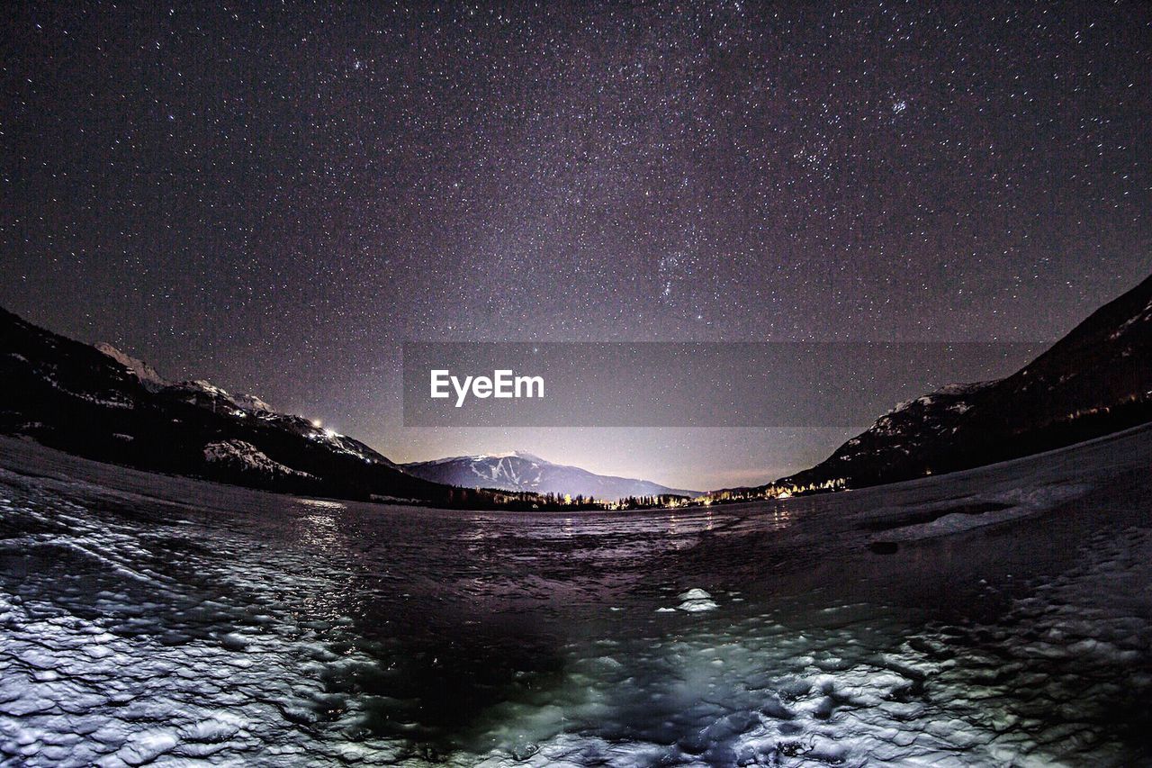 SCENIC VIEW OF LAKE AGAINST MOUNTAINS AT NIGHT