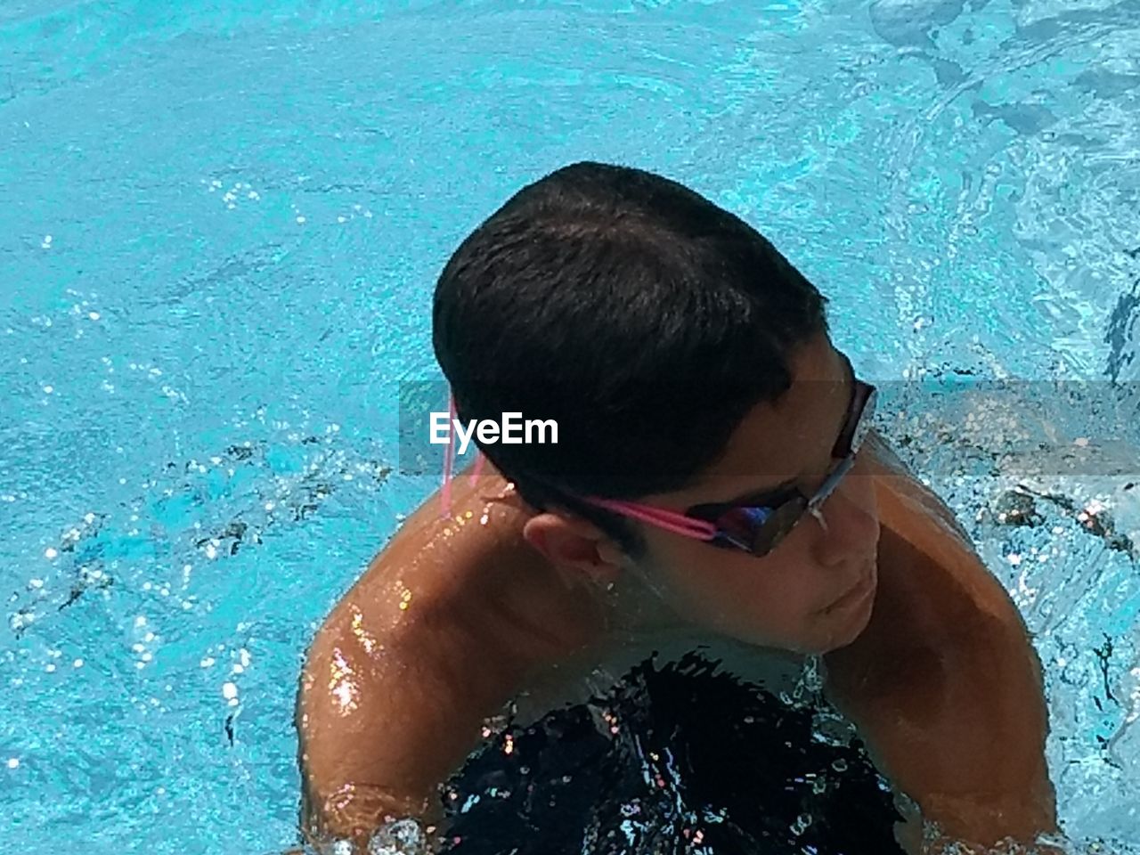 HIGH ANGLE VIEW OF SHIRTLESS SWIMMING IN POOL