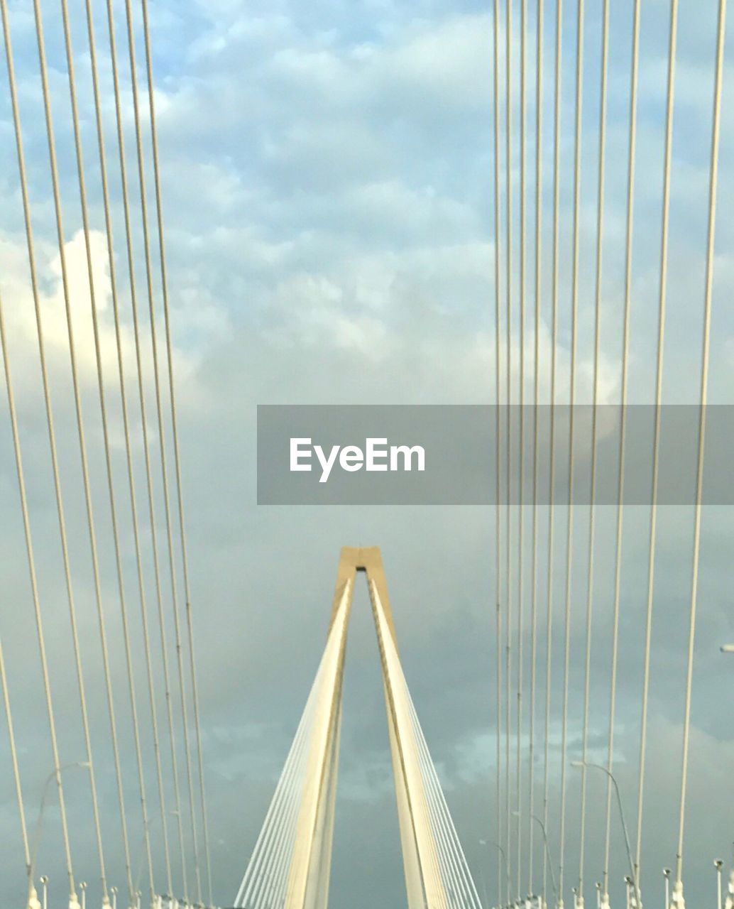 Suspension bridge against cloudy sky