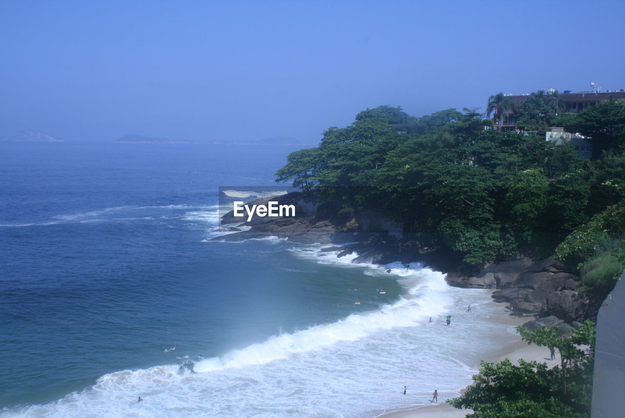 SCENIC VIEW OF SEA AND TREES AGAINST BLUE SKY