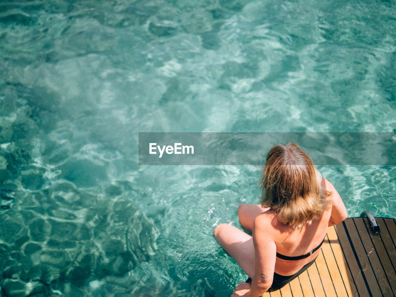 High angle view of woman sitting by sea on jetty