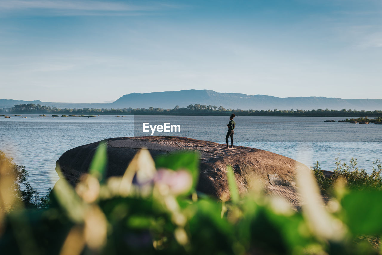 MAN STANDING BY LAKE