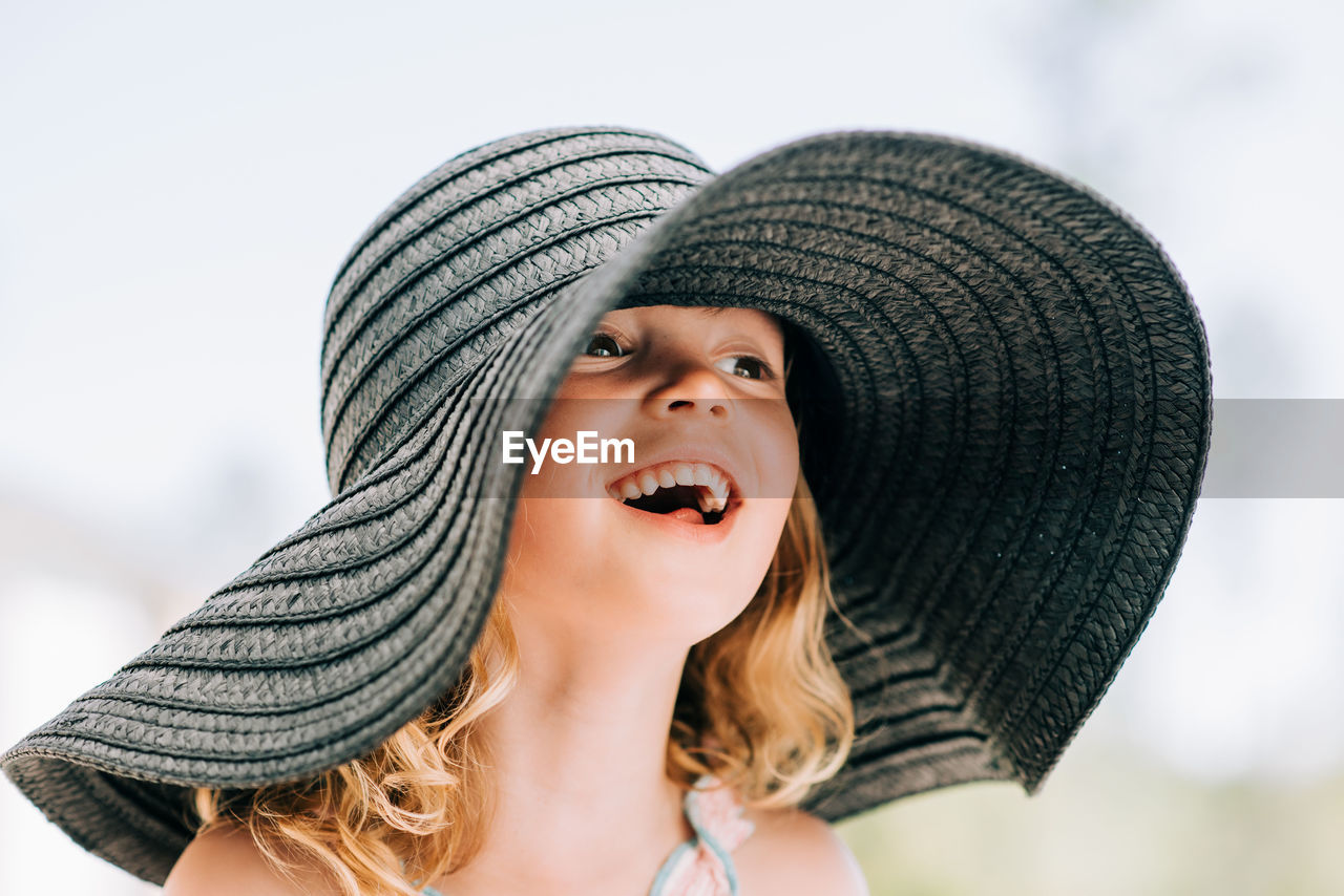 Portrait of a young girl smiling outside with a large sun hat on