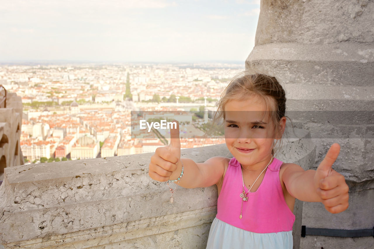 Smiling girl showing thumbs up outdoors