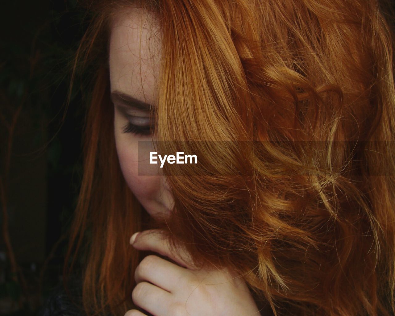 Close-up of beautiful redhead young woman against black background