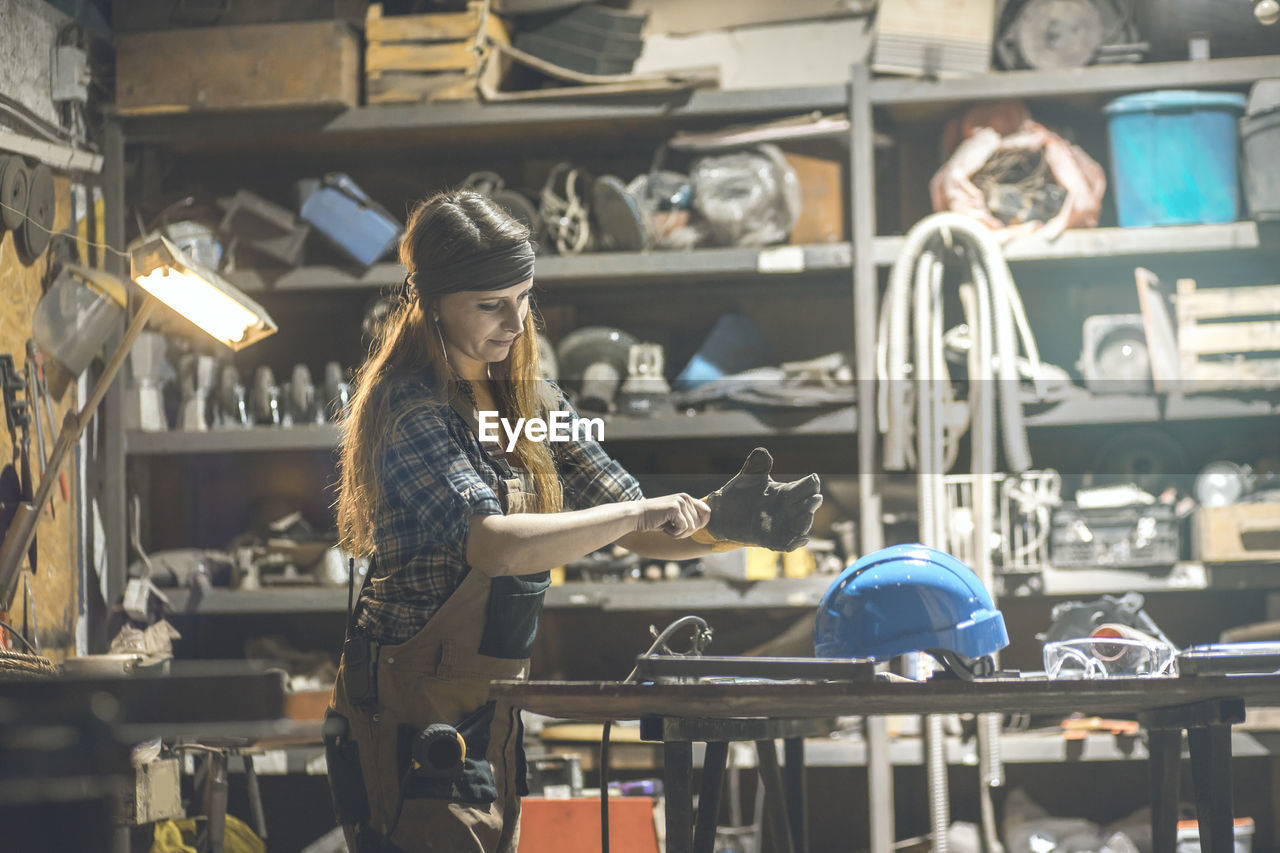 Woman wearing gloves while standing at table