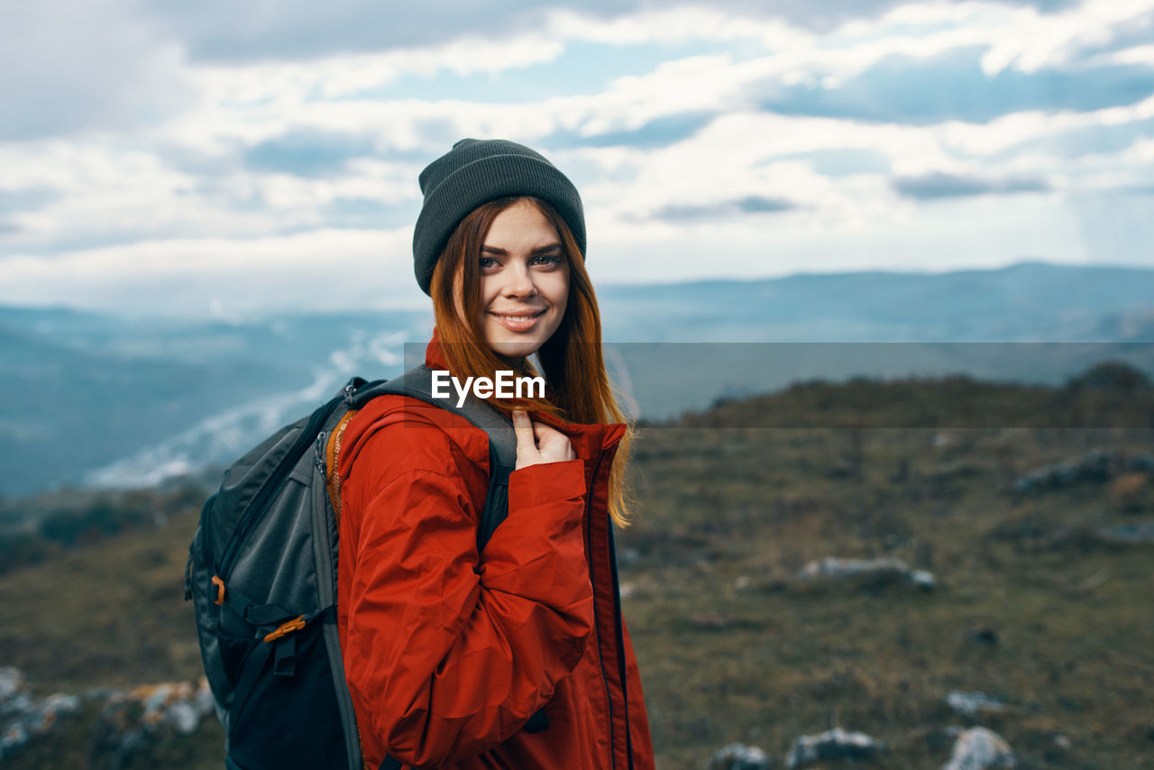 PORTRAIT OF WOMAN STANDING AGAINST SKY