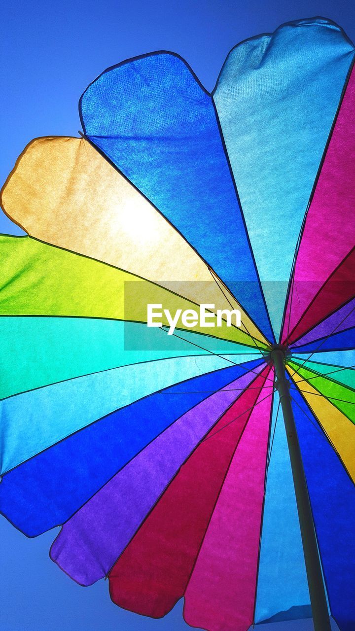 Low angle view of colorful beach umbrella against clear sky