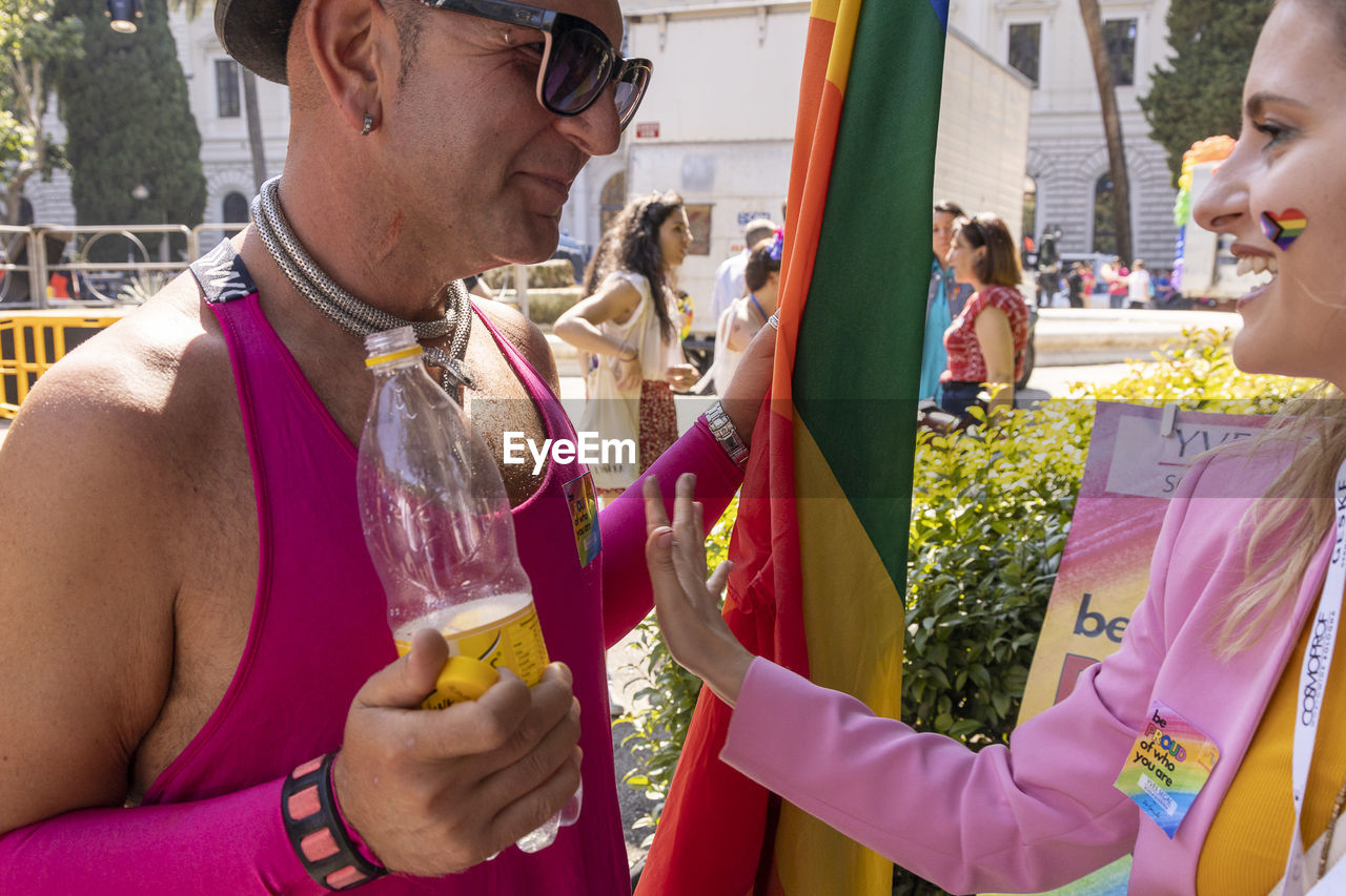 adult, festival, men, sunglasses, glasses, fashion, celebration, group of people, event, women, arts culture and entertainment, carnival, day, person, waist up, holding, togetherness, leisure activity, lifestyles, happiness, smiling, outdoors, clothing, young adult, emotion, friendship, architecture, headshot, nature, portrait