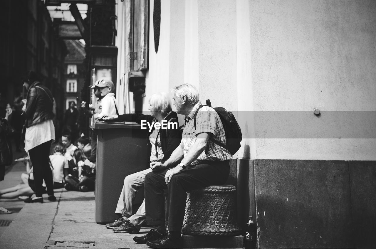PEOPLE SITTING ON CHAIR AT STREET