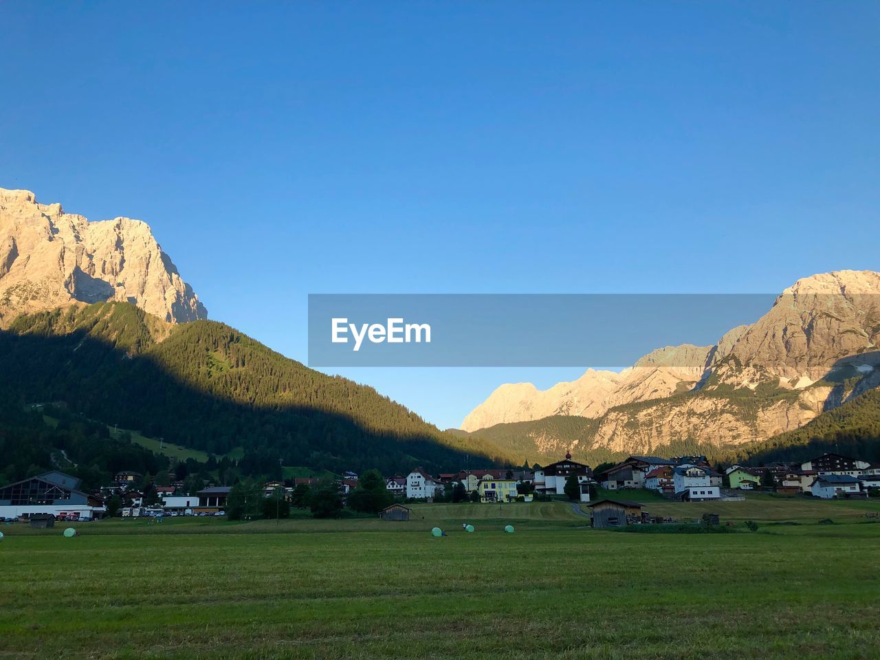 Scenic view of field and mountains against clear blue sky