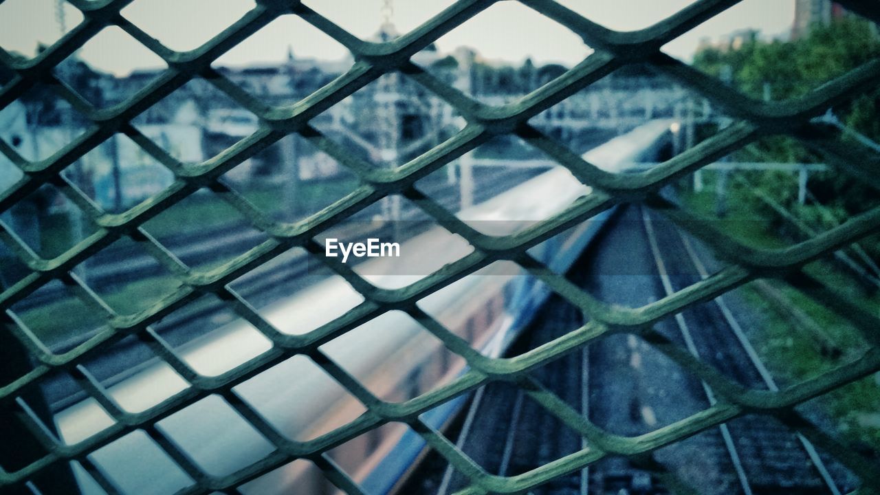 Blurred motion of train on railroad tracks seen through fence