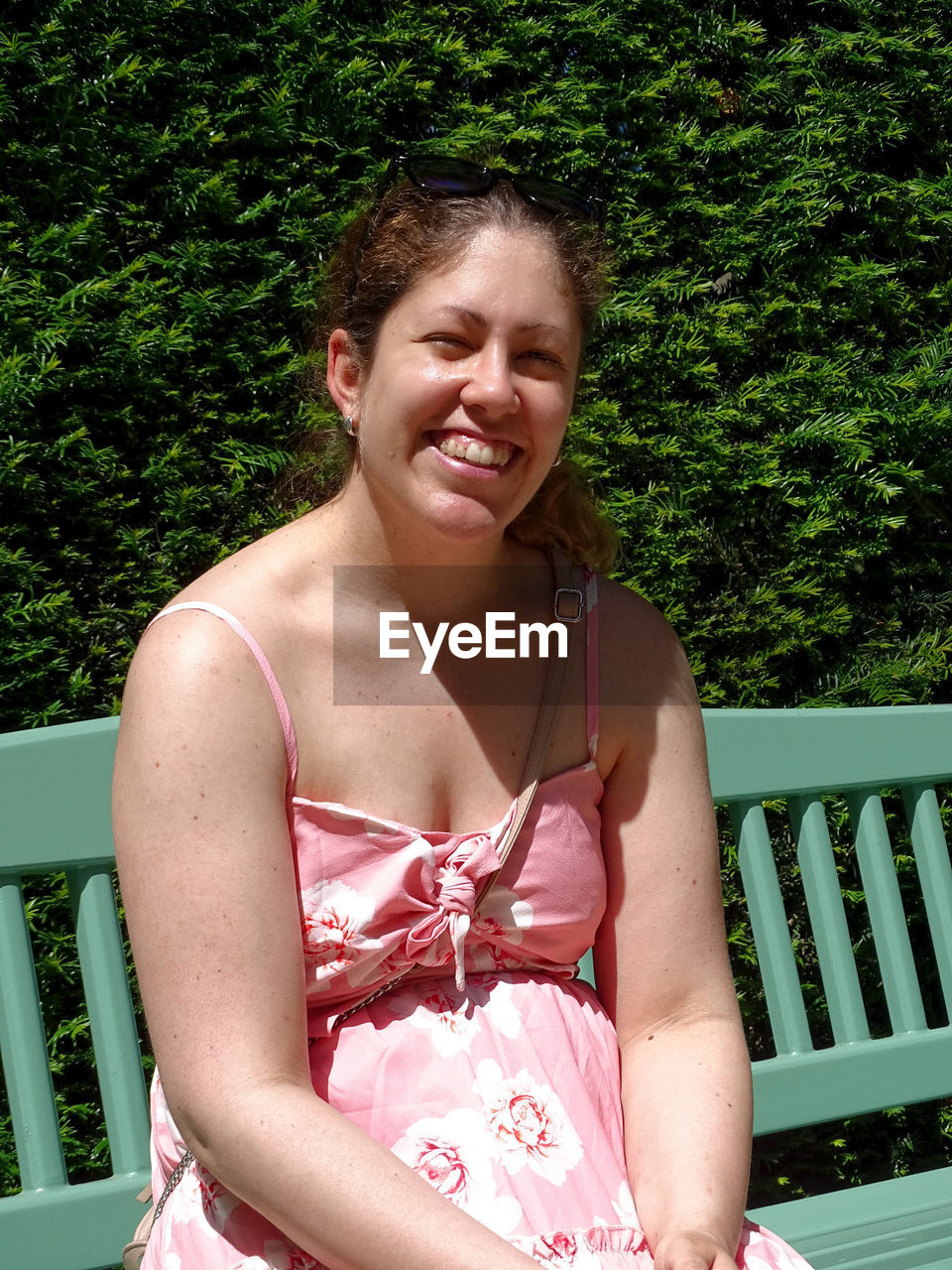 PORTRAIT OF A SMILING YOUNG WOMAN AGAINST TREES