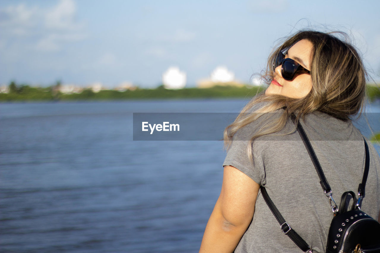 Woman in sunglasses against lake