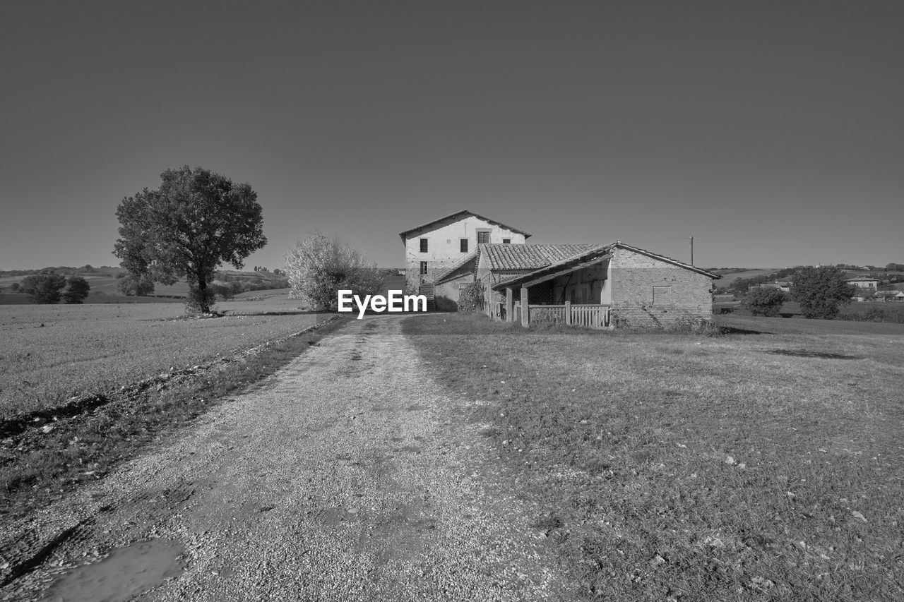 architecture, sky, built structure, black and white, building, monochrome, building exterior, landscape, house, nature, plant, no people, rural scene, monochrome photography, tree, land, rural area, environment, agricultural building, white, abandoned, residential district, field, farm, clear sky, copy space, road, outdoors, day, grass, scenics - nature, remote, farmhouse, non-urban scene