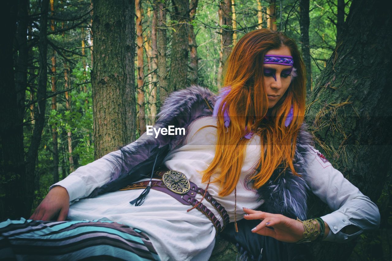 Redhead woman lying on tree trunk in forest