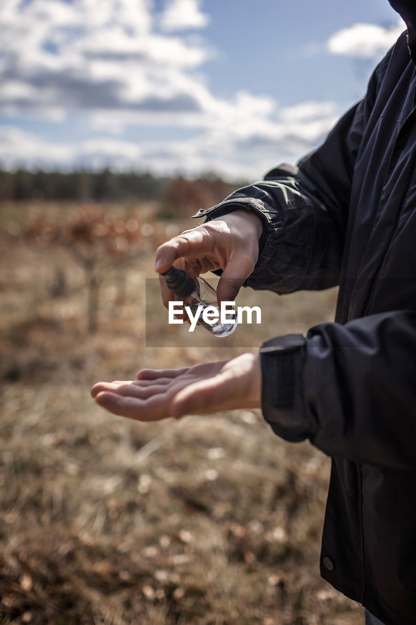 Midsection of man using hand sanitizer on field